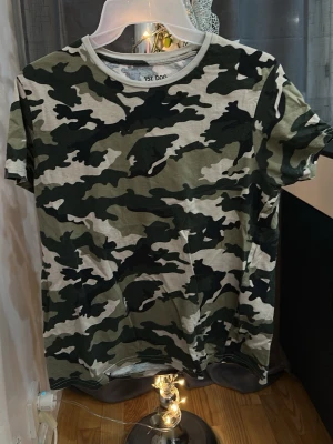 Camo t-shirt från 157 DOG - Snygg t-shirt från 157 DOG i klassiskt camouflage-mönster. T-shirten är kortärmad och har en relaxed passform, perfekt för en chill och trendig look. Tillverkad i mjuk bomull som känns skön mot huden.