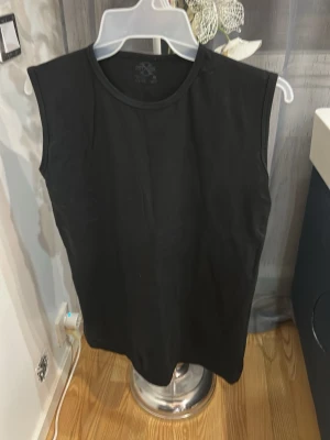 Svart ärmlös topp - En enkel svart ärmlös topp med rund halsringning. Perfekt basplagg som passar till det mesta. Tillverkad i mjukt material för en bekväm känsla.