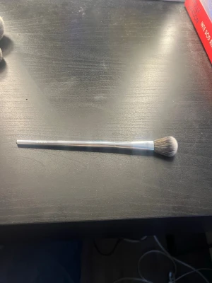 F20 Ögonskuggsborste från CAIA - Snygg ögonskuggsborste från CAIA med silverfärgat skaft och mjuka, täta borst i svart och vitt. Perfekt för att blenda ögonskugga och skapa snygga övergångar. Smal och lätt design som är enkel att använda för detaljerad applicering.