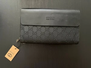 Stor Clutch  - Stor Clutch med sling till, så man kan bära den runt handleden. Finns även så man kan hålla på baksidan. Fack för kort, sedlar och mynt. Ytterligare ett fack för fler kort, sedlar mm. Stängs genom magnet. Helt ny med lapp på. Ungefär 22cm lång och 14cm hög