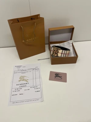 Bälte - Ett reversible bälte i färgen beige och svart med guldig logga. Den är helt ny, är 105 cm lång och det är bara bältet som ingår boxen o allt annat kommer inte med. Pris kan diskuteras och skriv om du har några frågor. 