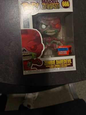 Funko Pop! Zombie Daredevil 666 - Säljer en Funko Pop! figur från Marvel Zombies-serien, nummer 666, föreställande Zombie Daredevil. Figuren är röd och grön med detaljer som visar zombielook och kommer i originalförpackning med 2020 Fall Convention Limited Edition-sticker.