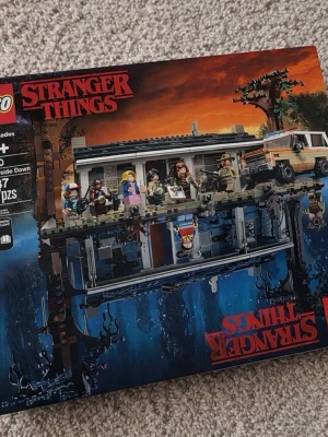  Stranger Things The Upside Down - Säljer ett LEGO-set från Stranger Things-serien, The Upside Down. Setet innehåller både huset och dess spegelvärld, samt flera minifigurer och en bil. Perfekt för fans av serien och LEGO-samlare.