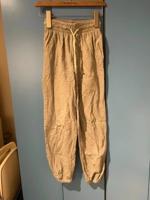 Beigea mjukisbyxor med snörning XS - Snygga och bekväma grå mjukisbyxor med dragsko i midjan och resår vid bensluten. Perfekta för chill dagar eller när du vill ha en avslappnad stil. Tillverkade i mjukt bomullsmaterial som känns skönt mot huden.