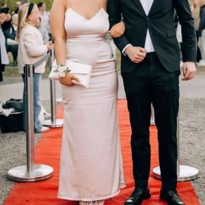 Balklänning - Säljer en elegant långklänning från Nelly i champagnefärgad satin. Klänningen har smala axelband, v-ringad urringning och figurnära passform som ger en snygg siluett. Den är lite djupare i ryggen. Perfekt för bal!! I storlek 38, men skulle säga att den passar en 36 med. Har sytt upp klännigen så den passar min längd ca 162 cm, på mig med klackar på 7 cm så gick klännigen till ca hälen. Pris går att diskutera!!! 🩷