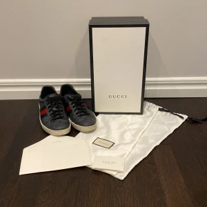 Svarta Gucci Ace sneakers - Sjukt snygga Gucci Ace skor i storlek 42,5. Riktigt bra skick på skorna då dom har använts varsamt. Nypris ca 8500kr medans vårt pris är 2500kr. Tvecka inte på att ställa frågor och priset är ej hugget i sten!