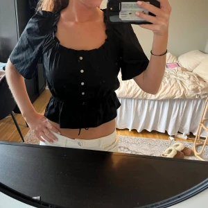 Svart blus med knappar och volang - Så fin och super bra skick då den aldrig är använd, endast provad. Storlek XXS men passar mig som oftast har Xs/S