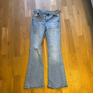 Ljusblå bootcut jeans - Jätte snygga ljusblå jeans med bootcut passform i stretchigt material och en slitning på höger ben. Midjemått rakt över: 32cm. Innerbenslängd: 70cm. En hälla på baksidan har lossnat lite men det är lätt att fixa. Pris kan diskuteras💕