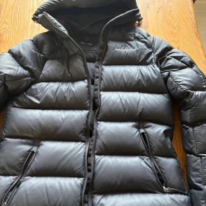 Svart dunjacka med huva från Peak performance  - Säljer en svart dunjacka från Peak Performance med stor luva. Inte en ända skråma på jackan, den är i princip oanvänd. NYPRIS 4199kr