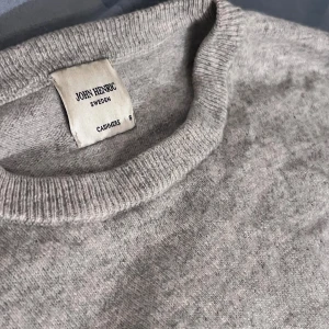 Grå  John Henric Cashmir tröja - Supermjuk och stilren grå tröja i 100% kashmir från John Henric. Klassisk rund halsringning och ribbade muddar. Den har också två defekter på vardera armbåge.Perfekt för dig som gillar en enkel men lyxig look. Passar lika bra till jeans som till kostymbyxor.🎉🎉