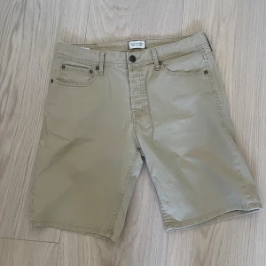 Beige shorts från Jack & Jones - Snygga beige shorts från Jack & Jones i bomull med klassisk femficksdesign och komfortabel passform. De har normal midja, bälteshällor och stängs med knapp och dragkedja. 