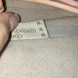 Beige fleecejacka Outdoor Discovery XL - Mjuk och varm beige fleecejacka från Outdoor Discovery i storlek XL. Jackan har en praktisk dragkedja framtill och ett broderat bergsmärke på bröstet. Perfekt för kyliga dagar och outdoor-aktiviteter. Fleece-materialet gör den extra skön att ha på sig.