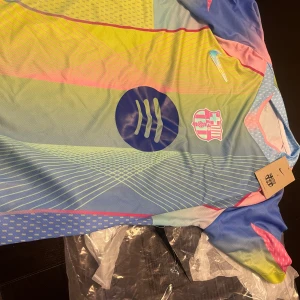 FC Barcelona x Nike färgglad fotbollströja - Säljer en unik FC Barcelona x Nike fotbollströja i flera färger med coola grafiska mönster. Tröjan har korta ärmar, klubbmärke och Nike-logga på bröstet samt Spotify-logga. Tillverkad i lätt och ventilerande material, perfekt för match eller träning.