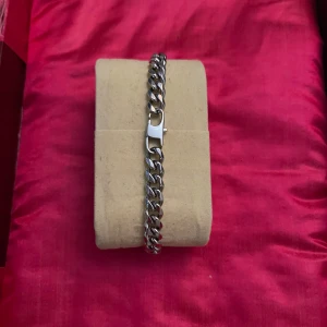 Silverfärgat kedjearmband E. Johanson - Stilrent armband i silverfärgad metall med kraftig kedja och robust lås. Längden är cirka 22 cm och armbandet har en klassisk, chunky look som passar dig som gillar att sticka ut med accessoarer.