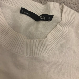 Vit tröja från 157, XS - En stilren vit tröja från 157 i storlek XS. Tröjan har rund halsringning, ribbade muddar och är tillverkad i ett mjukt material som känns skönt mot huden. Perfekt för lager-på-lager och enkel att matcha med andra plagg.
