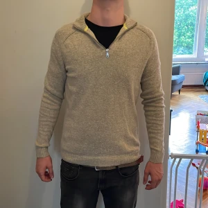 Beige half zip tröja Only & Sons - Beige stickad tröja från Only & Sons med halv dragkedja och ribbade muddar. Tröjan har en klassisk krage med gul detalj på insidan och är långärmad. Materialet är en mix av bomull och ull, perfekt för kyligare dagar. Modellen är 178 cm lång och väger 63 kg. Det är bara att höra av sig vid frågor och funderingar 😀