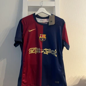 FC Barcelona matchtröja Nike S - Snygg FC Barcelona matchtröja från Nike i klassiska rödblå färger. Tröjan har klubbmärke på bröstet, guldfärgade detaljer och tryck, samt Dri-FIT-material som andas. Kortärmad modell med rak passform och officiella loggor både fram och bak.
