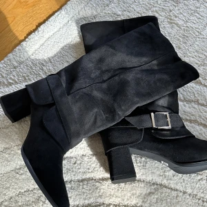 Boots med spänne - ALDRIG ANVÄNDA! Endast testade.   Har suttit i min garderob i ett år nu så dags att sälja. Står storlek 40 men känns som 39.   Högklackade boots i sammetmaterial med snyggt spänne längst ner, perfekt för hösten för snygga outfits. ❤️  Klackan är 5cm hög. 