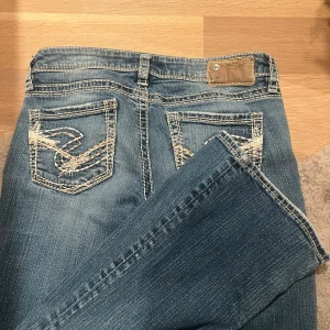 Silver Jeans bootcut jeans blå - Blå low waist jeans från Silver Jeans med snygga kontrastsömmar och broderade bakfickor. ❤️köpte för 900 kr aldrig använt där av priset.