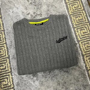 Grå kabelstickad tröja från Salming - Tröjan är använd någon gång men har inga deffekter. Köpt hos outlet sport butik för 800kr