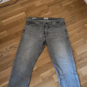 Grå relaxed jeans från Jack & Jones - Snygga grå jeans från Jack & Jones i relaxed fit-modellen Chris. Jeansen har klassisk femficksdesign, raka ben och en tvättad look. Perfekta för dig som gillar en lite lösare passform och streetig stil.