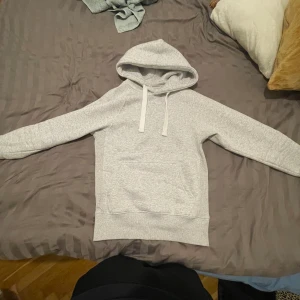 Ljusgrå hoodie med huva och ficka - Säljer en stilren ljusgrå hoodie med huva och dragsnören. Tröjan är från russemerch och är i nytt skick men prislapp är borta. Den är extremt skön o mjuk .