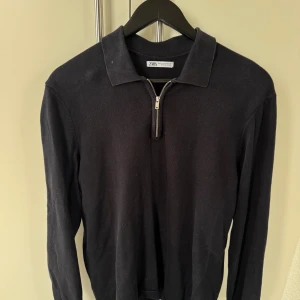 Svart half zip tröja från Zara - Svart långärmad tröja från Zara med krage och half zip-dragkedja framtill. Tröjan har en clean och stilren look, perfekt för dig som gillar minimalistisk stil. Materialet är mjukt och känns skönt mot huden.