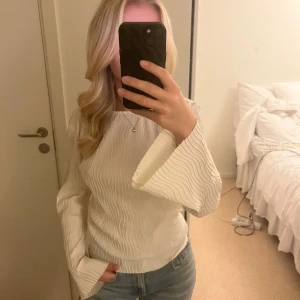 Vit blus med vida ärmar - Säljer en vit blus med snyggt vågigt mönster och vida långa ärmar. Blusen har en rak passform.