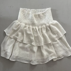 Vit volangkjol från Chelsea XS - Supersöt vit kjol från Chelsea. Använd ett par gånger, och finns tecken på använd. Har en fläck på ena sidan av kjolen (se bild). Köptes för 400kr. 