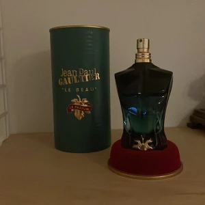 Jean Paul Gaultier Le Beau Parfym 75ml - Jean Paul Gaultier Le Beau Le Parfum i 75ml flaska. Flaskan har en cool kroppsliknande form i mörkgrönt och transparent glas med gulddetaljer. Kommer med original grön och guldig förpackning. En ikonisk och stilren herrdoft. Se bild 4 för att se hur mycket det är kvar