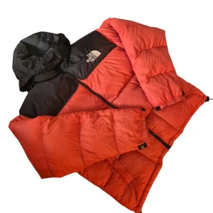 Röd och svart dunjacka The North Face size M - Säljer en fet dunjacka från The North Face i rött och svart. Jackan har huva, dragkedja framtill och justerbara muddar. Perfekt för kalla dagar och har en riktigt puffig look. Logga på bröstet och ryggen. Snygg och funktionell för vintern.