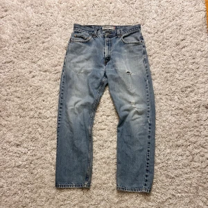 Ljusblåa Levi's 505 Regular Fit jeans  - Klassiska Levi's 505 jeans i ljusblå tvätt med skit snygga slitningar och två hål på höger ben, det är regular fit och sitter skit najs 