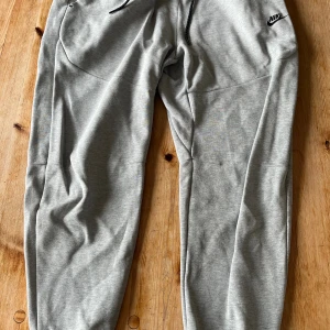 Nike tech fleece byxor grå - Gråa Nike tech fleece byxor i storlek XL. Dragkedjan är lite trasig men i övrigt är de i bra skick.