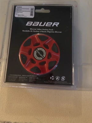 Bauer Slivvver Inline Hockeypuck röd - Säljer en röd Bauer Slivvver Inline Hockeypuck, perfekt för inlineshockey. Pucken är rund med flera öppningar och har en svart och vit mittdel med Bauer-logga. Tillverkad i slitstark plast och levereras i originalförpackning.