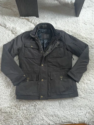 Massimo Dutti Fieldjacket: S - Säljer en superfin fodrad fieldjacket från Massimo Dutti. Jackan är fodrad vilket gör den grym för kyligare dagar🤩. Den är i storlek M men sitter som S. Jackan har även en luva som fälls ut baktill genom kragen. Hör av er vid yttligare frågor☺️(Jackan är brun men ser lite grå ut i bilderna pga dåligt ljus)