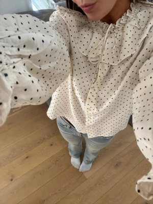 Vit blus med svarta prickar och volang - Super fin blus från HM i strl M. Endast använd vid ett tillfälle. 