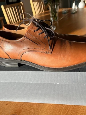 Bruna läderskor med snörning - Snygga bruna läderskor med klassisk design och svarta snören. Märke ZEUS feån Scorette. Skorna har en låg klack och stilrena sömmar längs sidorna. Perfekta för dig som gillar en tidlös och clean look. Passar till både jeans och kostym. Använda en gång. Nypris 1299kr