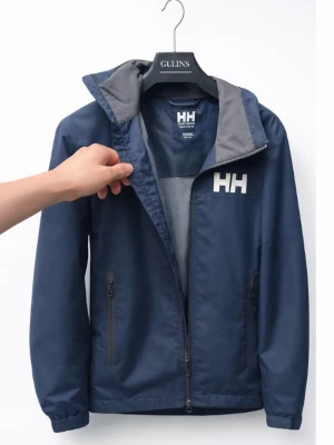 Blå vindjacka från Helly Hansen - Snygg marinblå vindjacka från Helly Hansen med vit HH-logga på bröstet. Jackan har dragkedja framtill, två sidofickor med dragkedja och meshfoder. Ståkrage med grå insida och minimalistisk design. Perfekt för blåsiga dagar.
