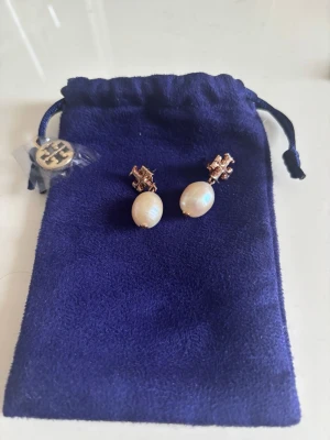 Tory Burch örhängen med pärlor - Snygga örhängen från Tory Burch med roseguld loggor.