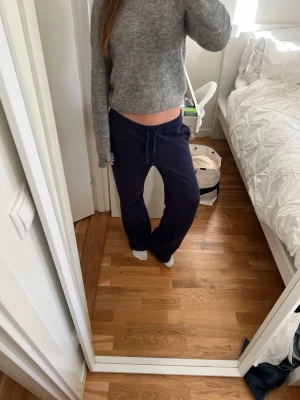 Mörkblå mjukisbyxor med dragsko - Säljer ett par mörkblå mjukisbyxor med avslappnad passform och dragsko i midjan. Byxorna har raka ben och är perfekta för chill dagar hemma eller när du vill vara bekväm. Materialet känns mjukt och stretchigt.