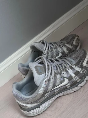 Nike p6000 - Nike p6000 sneakers i olika nyanser av grått med silvriga detaljer. Ovandelen är i mesh och syntetmaterial för bra andningsförmåga och komfort. Klassisk Nike Swoosh på sidan och robust sula för extra stöd. Perfekta för dig som gillar sportig och stilren look. Även här så tvättar jag dom innan jag skickar⭐️🙌