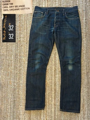 Nudie Jeans Selvedge  - Säljer mina Nudie Jeans Selvedge, modellen är Grim Tim i storleken 32/32. Jeansens selvedge-denim är riktigt snygg och håller formen bra, och de får en fin naturlig patina ju mer man använder dem.  Mått här 👇  Innerbenslängd: 75 cm Totallängd: 105 cm Midjabredd: 43 cm  Benslut: 19 cm  Skick: 	•	De är i fint skick med riktigt snygga fades!  	•	De har ett hål i grenen men den får man lagat gratis av Nudie! Jag kan fixa det om de är aktuellt!  	•	Grim Tim är nudies mest populära modell och sitter b