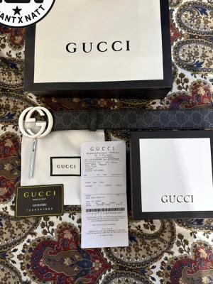 Gucci GG Supreme bälte med silverfärgat spänne - Snyggt bälte från Gucci i GG Supreme-mönstrat grått canvasmaterial med ett stort, silverfärgat GG-spänne. Bältet har klassisk design och levereras med originalförpackning, dustbag och äkthetskort.