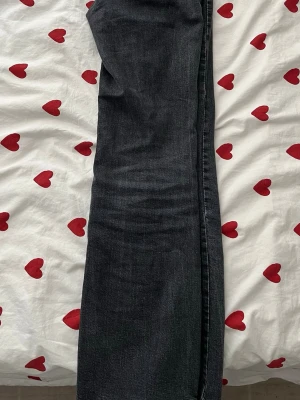 Svarta raka jeans från Ginatricot - Säljer ett par svarta raka jeans från ginatricot med klassisk femficksdesign och silverfärgade detaljer. Jeansen har en snygg tvättad finish och är tillverkade i bomull. Perfekta för en avslappnad och trendig stil.