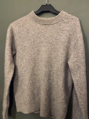 Grå merinoulltröja från Vailent - Mysig grå stickad tröja från Vailent i mjuk merinoull. Klassisk rund halsringning och ribbade muddar vid ärmslut och nederkant. Perfekt för lager på lager under kyliga dagar.