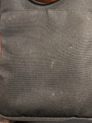 Svart datorväska med fickor - En stilren svart datorväska i tyg med praktiska innerfickor och ljusgrått foder. Väskan har en enkel design och dragkedja upptill, perfekt för att organisera laptop och tillbehör. Passar dig som vill ha en clean och funktionell look.