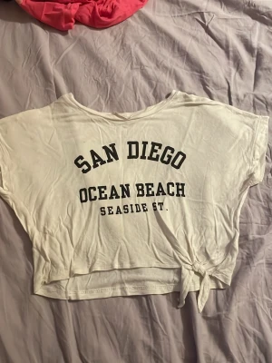 Mag tröja  - Cropped vitt top. Använd 1-3 gånger. En liten fläck finns på baksidan av tröjan. Fläcken visas på bild