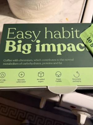 Kaffe med krom i grön förpackning - Säljer ett kaffe med krom som bidrar till normal ämnesomsättning av kolhydrater, protein och fett. Förpackningen är grön och har symboler för veganskt, inget tillsatt socker, naturligt koffein och återvinningsbar förpackning. Perfekt för dig som vill ha ett enkelt och hälsosamt kaffe.