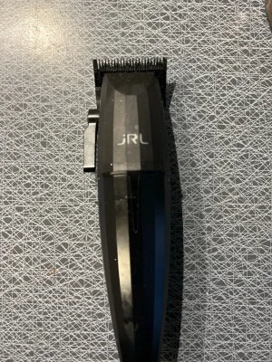 JRL svart clipper  - Snygg svart hårtrimmer från JRL med ergonomiskt handtag och justerbar klipplängd. Tillverkad i slitstark plast och metall, perfekt för att fixa frisyren hemma. Enkel att använda och ger ett proffsigt resultat.
