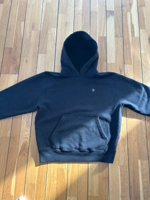 Polar Svart hoodie 100% bomull - Svart hoodie från Polar med klassisk känguruficka och liten broderad logga på bröstet. Mjuk bomullskänsla och ribbade muddar vid ärmslut och midja. Perfekt för en avslappnad streetwear-look.